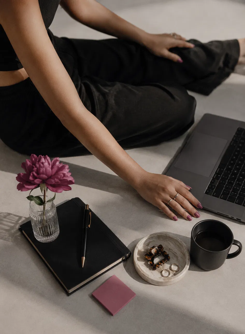 Entrepreneur working on laptop with notebook and flower