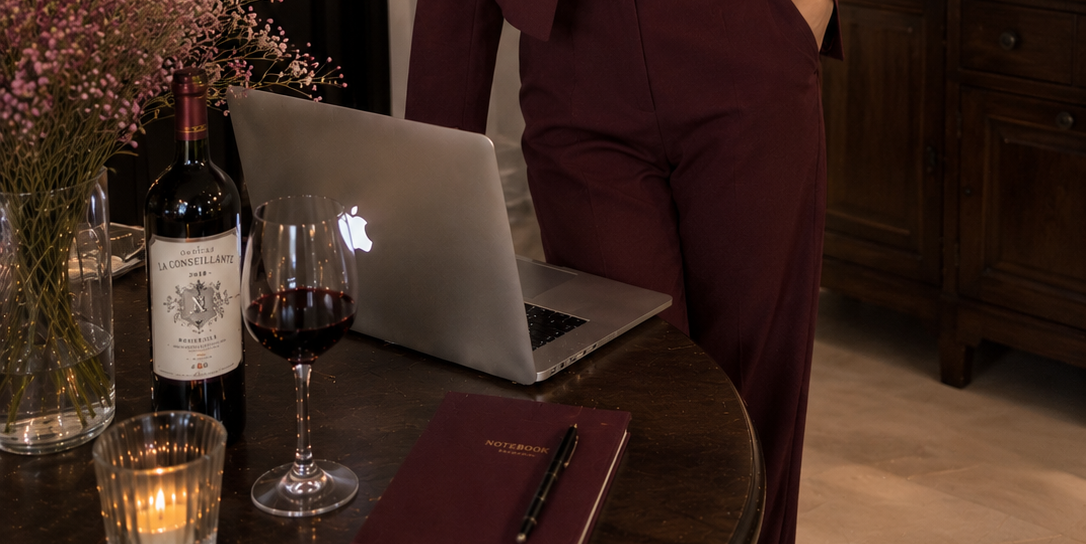 Designer in a wine suit at a candlelit table with laptop